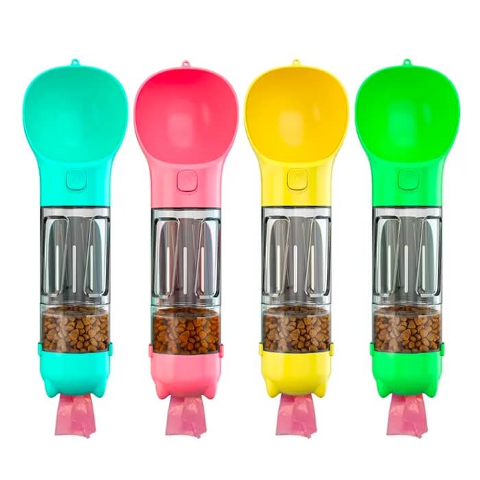 Quatro bebedouros e dispensadores de ração portáteis 5 em 1 para pets, apresentados lado a lado em cores vibrantes: verde-água, rosa, amarelo e verde. Cada um possui um compartimento transparente para ração e um compartimento colorido na parte superior que serve como bebedouro. A base de cada um tem uma pequena tigela destacável da mesma cor que o bebedouro