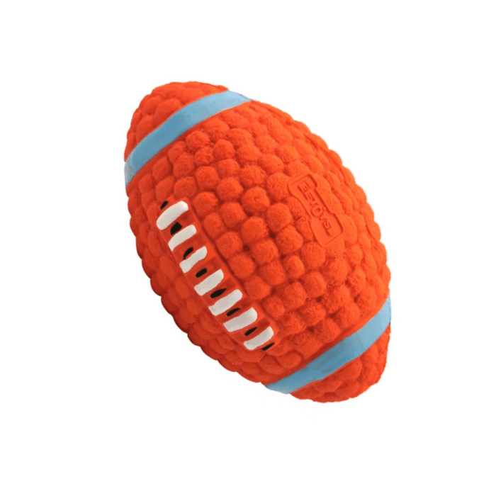 Brinquedo para cachorro em formato de bola de futebol americano, predominantemente laranja com detalhes em azul claro e branco. A textura é formada por várias saliências arredondadas, e há sulcos brancos que lembram as costuras de uma bola de futebol americano. O logotipo da marca está em relevo na superfície superior.