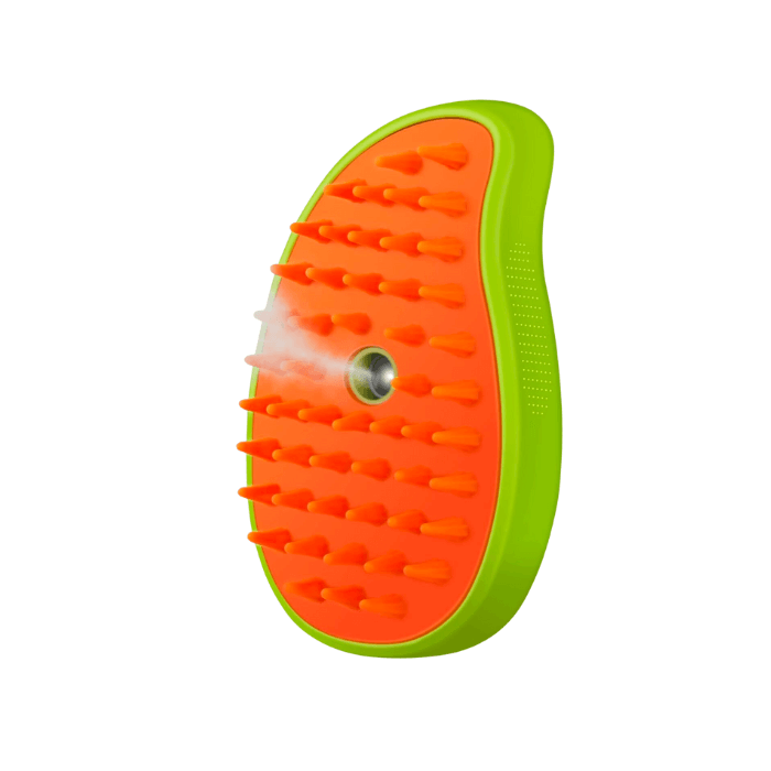 Escova a vapor 3 em 1 para gatos, com formato ergonômico de meia-lua e cores vibrantes em verde-limão e laranja. O lado laranja possui cerdas suaves de silicone para uma limpeza delicada e confortável, enquanto o centro apresenta uma abertura para a saída de vapor, destinada a suavizar e higienizar o pelo do gato durante a escovação.